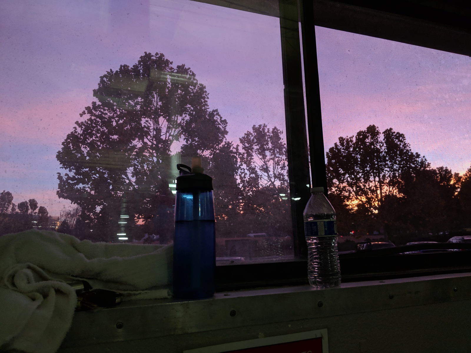 sunset-painted sky through a window, with water bottles and other gym accoutrements in the foreground